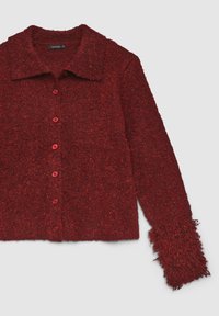 Roter Strickjacke mit strukturierter Oberfläche, Kragen, sechs Knöpfen vorne und plüschigen, ausgefransten Ärmeln. Das Material wirkt weich und kuschelig.