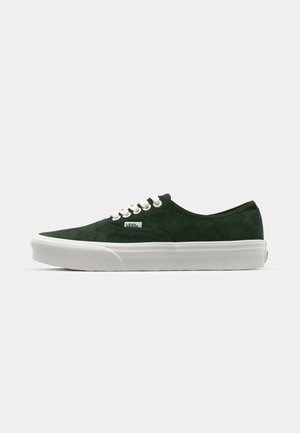 Grüne Wildledersneaker mit weißer Gummisohle, runden Schnürsenkeln und einem kleinen Logosticker an der Seite. Klassisches niedrigräusiges Design.