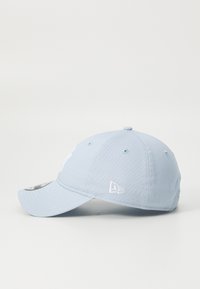 Light blue baseball cap made of fabric, featuring a curved brim and embroidered logo on the front, with ventilation holes on the sides.