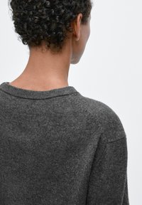 Dunkelgrauer Strickpullover mit weitem Rundhalsausschnitt, zeigt eine weiche Textur und einen lockeren Schnitt. Rückansicht zeigt minimale Nähte und eine strukturierte Schulter.