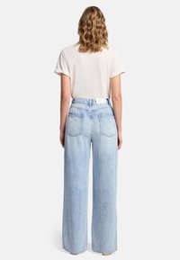 Jeans a gamba larga in denim di un azzurro chiaro, a vita alta, con un design a cinque tasche e un dettaglio minimale dei passanti per la cintura.