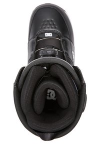Botte de snowboard noire avec un extérieur lisse, un intérieur rembourré et un dispositif de fermeture rond au niveau du col. Présente des bords renforcés et un doublage intérieur.