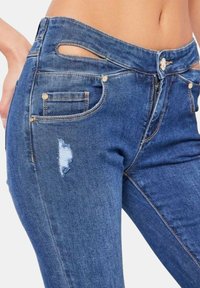 Jeans in denim blu con una toppa invecchiata, particolari in oro e un taglio unico sulla cintura, dotati di tasche frontali e posteriori standard.