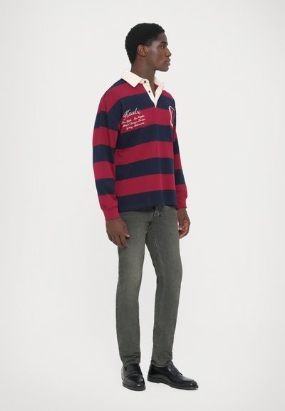 Red and navy striped long-sleeve polo shirt with a cream collar; paired with gray slim-fit jeans and black shoes. Features embroidered branding.