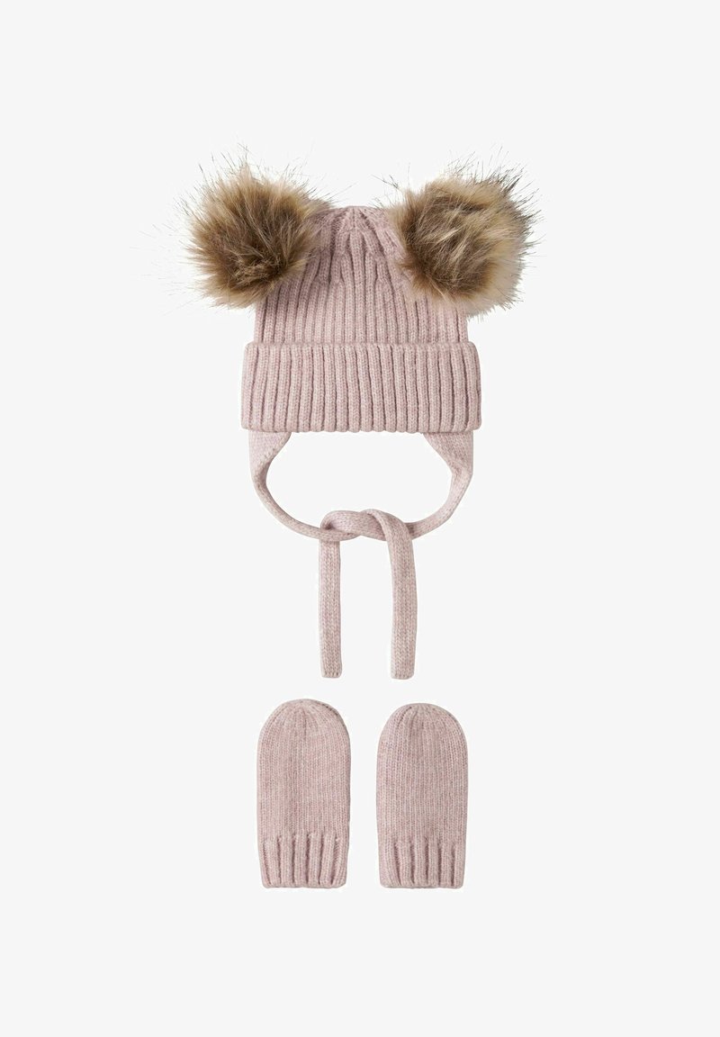 Bonnet de bébé tricoté rose avec deux pompons en fourrure et des moufles assorties, tous deux avec des détails côtelés et des cordons noués sous le bonnet.