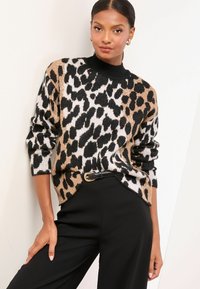 Leopardimustriga sviiter, mis sisaldab musta, beeži ja valget värvi segu, musta soonikkrae ja lõdvema kujundusega. Komplektis mustad püksid.