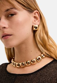 Set di gioielli in tono oro composto da una collana chunky con maglie quadrate e orecchini a bottone quadrati abbinati, entrambi con superfici lisce e lucide.