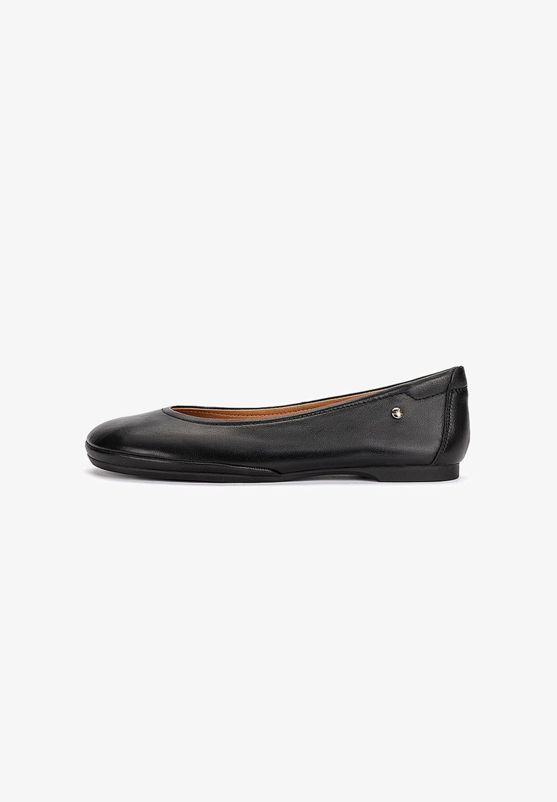 Ballerine plate en cuir noir avec bout arrondi, petit talon et petit détail de logo métallique près du talon, vue de profil latéral.