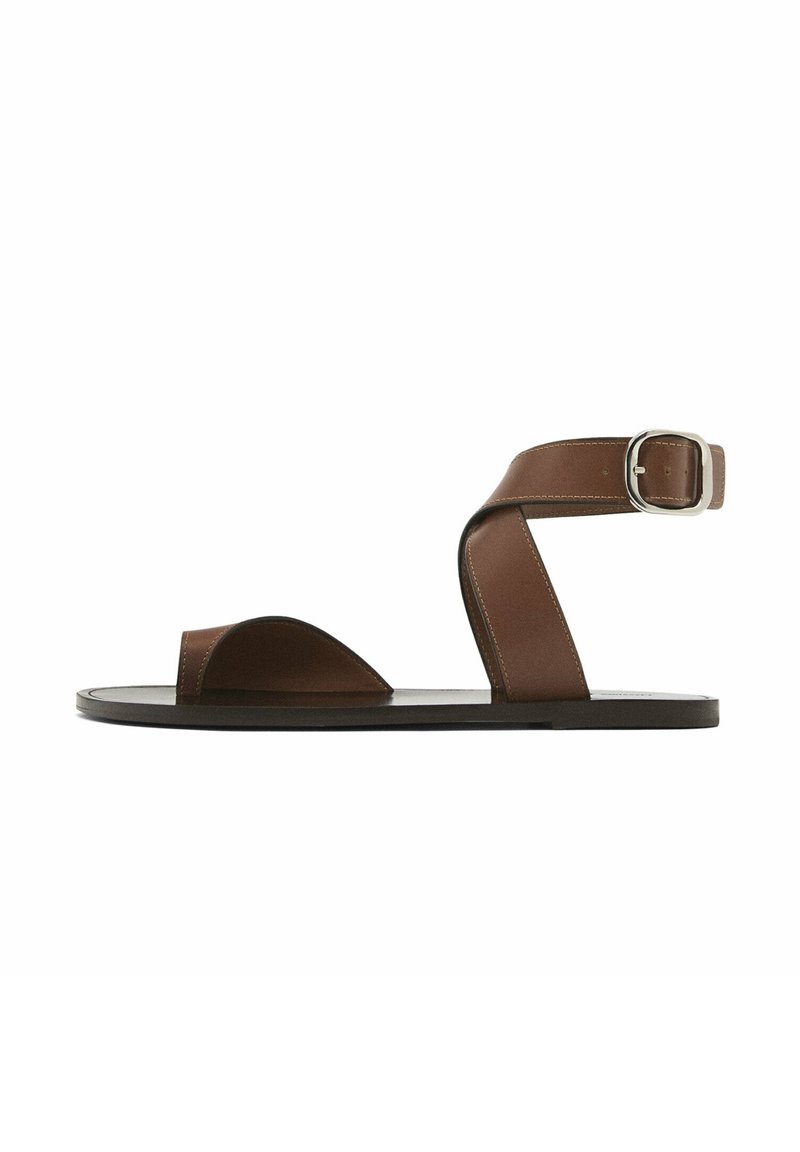 Sandales en cuir marron avec une large bride sur le pied et une fermeture à boucle à la cheville. Texture lisse avec un design minimaliste.
