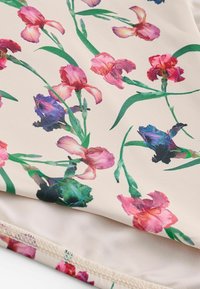 Fabric with a floral pattern featuring pink, purple, and red irises with green stems on a light beige background.