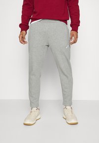 Grå bomullssweatpants med en avsmalnande passform och sidofickor, med en liten vit Nike-logotyp på vänstra låret.