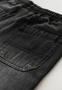 Pantaloni negri din denim cu talie elastică, cusături vizibile și un accent pe buzunarul din spate, având o textură ușor spălată.