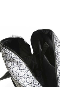 Black and white floral-patterned bag with a zip closure. Interior features a smooth black lining and a side pocket with a velcro strap.