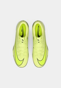 Neonsko žute Nike Mercurial nogometne kopačke s crnim swoosh logotipima prikazane od gore na jednostavnoj bijeloj pozadini.