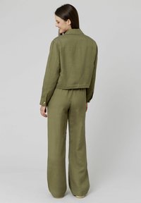Veste en lin vert olive au design cropped, dotée d'un col pointu et de poignets boutonnés, assortie à un pantalon large.