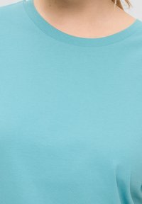 Helles blaues Baumwoll-T-Shirt mit rundem Ausschnitt und kurzen Ärmeln. Der Stoff ist glatt, hat eine einheitliche Textur und keine sichtbaren Muster.