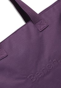 Paarse totebag van textuurstof, met twee stevige handvatten en een reliëflogo. Eenvoudige rechthoekige vorm, geschikt voor verschillende toepassingen.