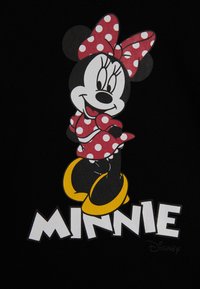 Grafica di Minnie Mouse su tessuto nero; presenta un vestito a pois rossi e un fiocco, scarpe gialle e il testo "MINNIE" in lettere bianche in grassetto.