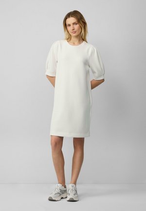 Witte, korte jurk met korte mouwen en een ronde hals, in een ontspannen pasvorm, gemaakt van een gladde stof, gecombineerd met lichtgrijze chunky sneakers.