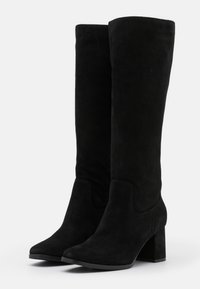 Botas altas de ante negro hasta la rodilla con punta afilada y tacón ancho. Textura suave, diseño sin costuras y ligera curva en la parte superior.
