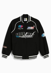 Zwarte bomberjack met witte strepen. Voorzien van kleurrijke geborduurde patches en tekst, en twee zijzakken. Zacht materiaal, relaxte pasvorm.