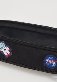 Sort penal lavet af stof, prydet med astronaut- og NASA-logo patches. Det har en lynlåslukning og en glat indvendig foret.