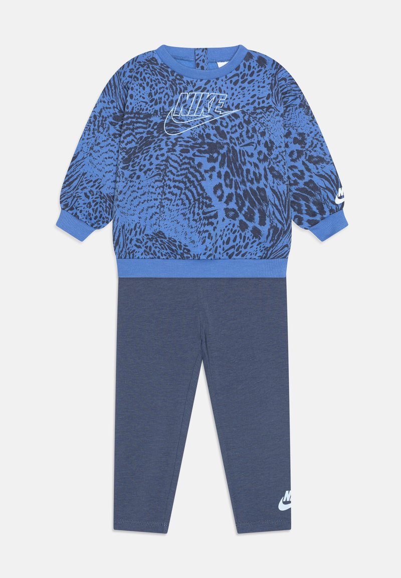 Sweatshirt bleu avec un imprimé animal noir et un logo Nike blanc sur la poitrine, associé à un legging bleu foncé avec un logo Nike blanc.