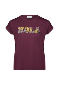 Bordeauxfarbenes T-Shirt mit kurzen Ärmeln, das mit floral inspirierten, strukturierten Applikationen in Gelb, Grau und Weiß das Wort "HOLA" zeigt.