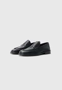 Mocassini in pelle nera con parte anteriore testurizzata, lati lisci e suola in gomma. Presentano un delicato design cucito e uno stile slip-on.