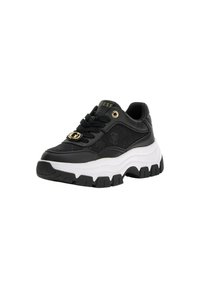 Sneaker sportive nere con tomaia in tessuto testurizzato, suola bianca spessa e dettagli in hardware dorato. Presentano lacci e un logo in forma discreta.