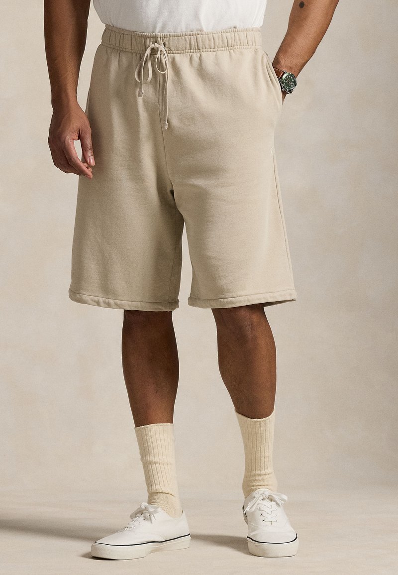Beige bomullsshorts med elastisk midjebånd og snor. Har sidelommer og en avslappet passform, som ender rett over kneet.