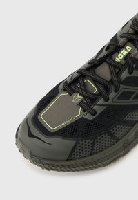 Μαύρο και γκρι παπούτσι για τρέξιμο σε μονοπάτια Hoka Speedgoat 2 με διάτρητο διχτυωτό σχεδιασμό, ενισχυμένη μύτη και μαύρα κορδόνια σε λευκό  φόντο.