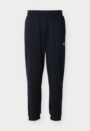 Zwarte taps toelopende joggingbroek met elastische tailleband, zijzakken, klein logo op de dij en geribbelde boorden met ritssluitingen bij de enkels.