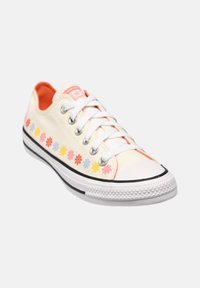 Zapatillas de lona en color crema con bordado floral multicolor a lo largo del costado, cordones blancos, forro interior naranja y suela de goma negra.
