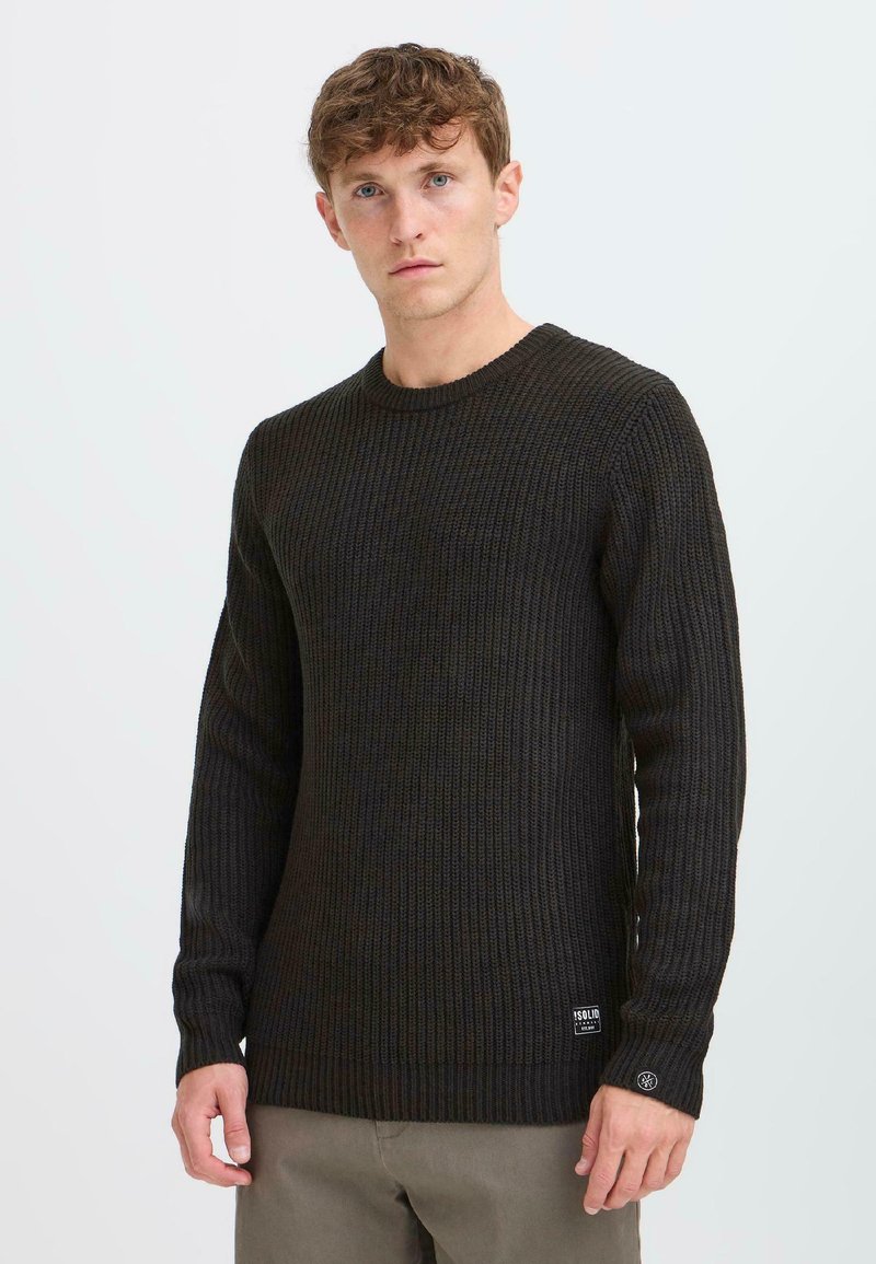 Dunkel gerippter Strickpullover mit langen Ärmeln und Rundhalsausschnitt. Verfügt über eine strukturierte Oberfläche und ein kleines Logoschild am unteren Saum.