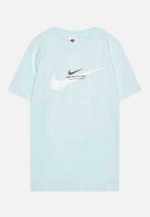 T-shirt en coton bleu clair avec un col rond classique. Présente un grand swoosh Nike blanc et une inscription noire sur le devant.