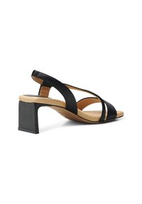 Mustasukka nahkainen paksu korko-sandaali, jossa on ristikkäiset remmit, avoin takapuoli ja teksturoitu sisäpohja. Neliömäinen korko ja sileä beige sisäpohja.