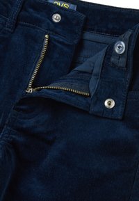 Marineblauwe corduroy broek met een ritssluiting, voorzien van een gouden metalen rits en knoopsluiting, en een gestructureerde ribstoffen voor extra detail.