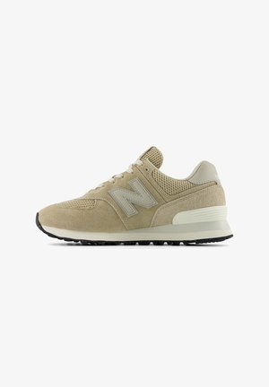 Beige New Balance-sneaker met suède en mesh bovenwerk, beige veters, een gevoerde zool en een zwarte, gestructureerde buitenzool, zijaanzicht.