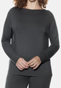 Grijze langemouwtop met een wijde halslijn en een losse pasvorm. Gemaakt van zacht materiaal met minimale stikseldetails en geen zichtbare patronen.