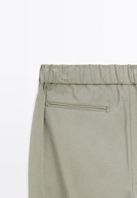 Pantaloni in tessuto verde chiaro e textured con vita elasticizzata arricciata e una piccola tasca sul retro con zip per un deposito sicuro.