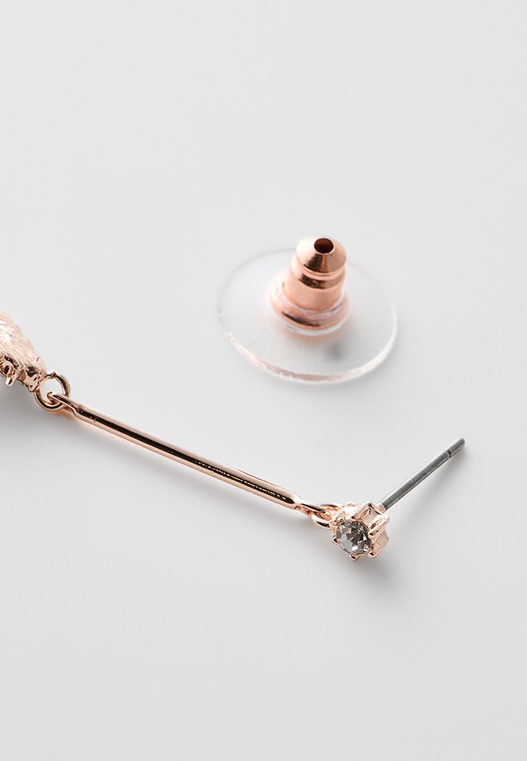 Orecchino in oro rosa con una piccola pietra chiara e un retro a farfalla trasparente separato su una superficie bianca.