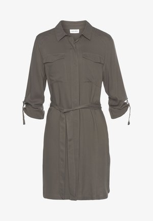 Sukienka koszulowa w kolorze oliwkowej zieleni z kołnierzykiem, długimi rękawami i dwoma kieszeniami na piersi. Posiada pasek w talii oraz podwijane mankiety rękawów.