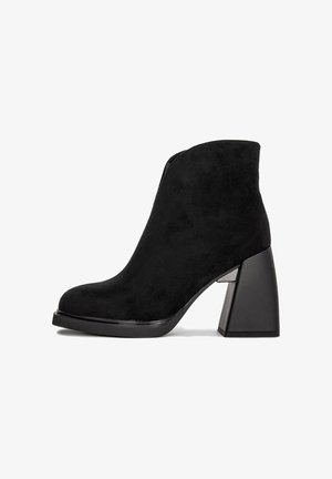 Czarne zamszowe botki za kostkę z masywnym obcasem i zaokrąglonym noskiem, przedstawione w profilu na białym tle.