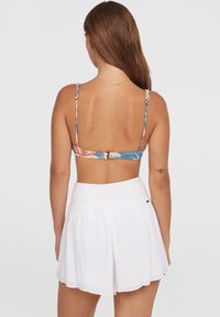 Bikini top met bloemprint, voorzien van dunne verstelbare schouderbandjes en een klittenbandsluiting aan de achterkant, gecombineerd met lichte witte high-waisted shorts met een smocktaille.