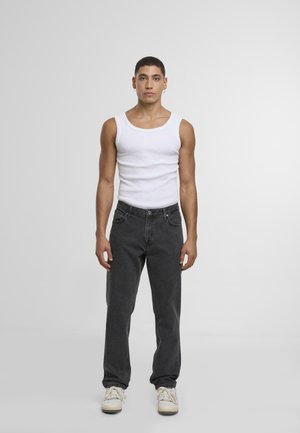 Hvid ærmeløs tanktop, sorte jeans og hvide sneakers. Jeansene har en lige pasform og et klassisk fem-lommes design.