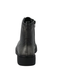 Botín negro de cuero hasta el tobillo con una textura suave, punta redondeada y cremallera lateral. Presenta una suela de goma negra baja y costuras mínimas.