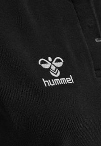Svart tyg med strukturerad yta som visar en vit broderad logotyp av en bi och ordet "hummel" under.