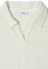 Polo texturé à rayures vert pâle et blanc avec un col ouvert et une étiquette de marque CECIL à l'intérieur du col.