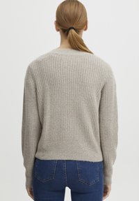 Beige ribbestrikket genser med lange ermer, rund hals og en lett croppet bak. Myk stofftekstur med et enkelt design.